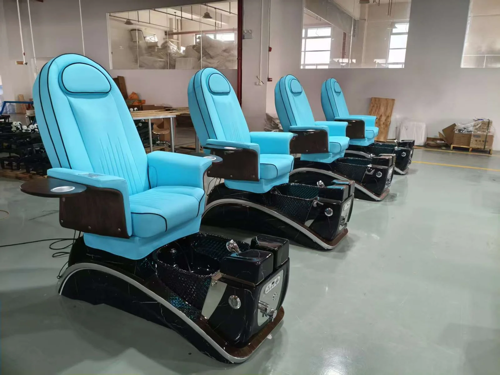 Blue-upholstered pedicure chairs lined up in the workshop